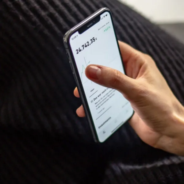 Hand hält ein Smartphone mit Depotübersicht